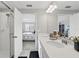 Bright bathroom featuring double sinks, quartz countertops, and a glass-enclosed shower visible from the bedroom at 319 Smugglers Way, Apopka, FL 32712