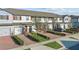 View of townhomes with gray-painted garages, red front doors, and manicured shrubbery at 319 Smugglers Way, Apopka, FL 32712