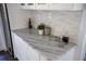 Kitchen showcasing white cabinets with light marble countertops and stacked stone backsplash at 4452 Fairview Ave, Orlando, FL 32804