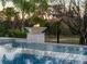 Outdoor fire feature and pool water feature with mature trees and greenery in the background at 480 Muirfield Loop, Reunion, FL 34747