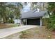 Light blue home boasts a long driveway leading to the black two car garage, surrounded by lush greenery at 509 Shane Cir, Winter Springs, FL 32708