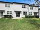 A well-manicured lawn and a back view of a modern white townhome with a sliding glass door at 532 Madison Dr, Davenport, FL 33837