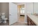 Bathroom view showing toilet, wood-look tile, vanity and open door to carpeted bedroom at 7517 Laureate Blvd # 4103, Orlando, FL 32827