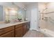 Bright bathroom with double vanity, wood cabinets, large mirror and tiled walk-in shower at 7517 Laureate Blvd # 4103, Orlando, FL 32827