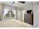 Bright bedroom featuring a ceiling fan, window with sheer curtains, wood flooring, and a wooden dresser at 7651 Whisper Way # 204, Reunion, FL 34747