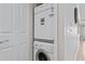 A stacked washer and dryer in a utility closet, next to a closed white door at 7651 Whisper Way # 204, Reunion, FL 34747