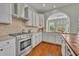 Kitchen featuring an oven, stone backsplash, white cabinets, and an arched view to the backyard at 807 Oak Shadows Rd, Celebration, FL 34747