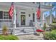 Inviting front porch with American flags, rocking chairs, and a decorative wreath on the front door at 807 Oak Shadows Rd, Celebration, FL 34747