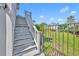 Exterior view of stairway and fenced yard with lush grass, landscaping and sunny sky at 807 Oak Shadows Rd, Celebration, FL 34747