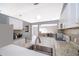 Kitchen with stainless steel sink, mosaic backsplash, white cabinetry, and view to living room at 1043 Meller Way, Orlando, FL 32825