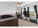 Bedroom features a bed, carpet floors, a ceiling fan, a window, and a desk with gaming equipment at 1129 Blue Garden Dr, Deland, FL 32720
