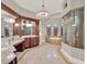 Luxurious bathroom with dual vanities, a jacuzzi tub, decorative tile, and a glass-enclosed shower at 11306 Bridge House Rd, Windermere, FL 34786