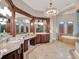 Bathroom featuring dual sink vanity areas with mirrors and cabinetry, a jacuzzi, and shower at 11306 Bridge House Rd, Windermere, FL 34786
