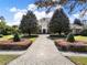 Elegant home features mature trees, manicured lawns, and a paved driveway in a lush, daytime setting at 11306 Bridge House Rd, Windermere, FL 34786