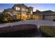 Luxury home boasts manicured bushes, a circular driveway, and warm lighting accentuating the facade at 11306 Bridge House Rd, Windermere, FL 34786