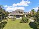 Expansive rear exterior featuring a well-manicured lawn, pool, and two-story home with a balcony at 11306 Bridge House Rd, Windermere, FL 34786
