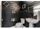 Chic powder room with black walls, decorative mirror and artwork, and a pedestal sink at 12189 Beach Fern Rd, Orlando, FL 32824