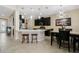 Modern kitchen featuring an island with seating, stone backsplash, stainless steel appliances, and black cabinetry at 12189 Beach Fern Rd, Orlando, FL 32824