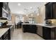 Modern kitchen featuring an island with seating, stainless steel appliances, black cabinetry, and dining area at 12189 Beach Fern Rd, Orlando, FL 32824