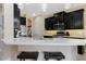 Close-up of modern kitchen island with seating, stainless steel appliances, and black cabinetry at 12189 Beach Fern Rd, Orlando, FL 32824