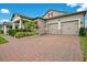 Driveway view of a two-car garage home featuring a manicured lawn and brick paved driveway at 13227 Spring Grove Way, Winter Garden, FL 34787