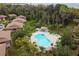 Aerial view showcasing a sparkling community pool surrounded by lush trees and condominium buildings at 170 Palmetto Woods Ct # 3A, Deltona, FL 32725