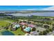 An aerial view shows the community center with pools, tennis courts, and a picturesque lake at 200 Snowy Orchid Way, Lake Alfred, FL 33850