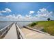 Scenic view of a wooden boat dock leading to a calm lake under a beautiful sky with white fluffy clouds at 200 Snowy Orchid Way, Lake Alfred, FL 33850