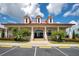 Exterior of a bright, well-maintained clubhouse with columns, palm trees, manicured landscaping, and ample parking at 200 Snowy Orchid Way, Lake Alfred, FL 33850
