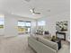 Bright upstairs living room with a sliding glass door to a deck area, neutral carpet, and a ceiling fan at 200 Snowy Orchid Way, Lake Alfred, FL 33850