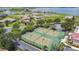 Aerial view of well-maintained tennis courts surrounded by lush landscaping and beautiful homes near a scenic lake at 200 Snowy Orchid Way, Lake Alfred, FL 33850