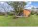 The backyard features a green lawn and mature trees, with a view of the home's exterior and screened-in patio at 2326 Wintermere Pointe Dr, Winter Garden, FL 34787