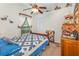 A quaint bedroom features a ceiling fan, a window with curtains, and a comfortable bed with blue heart-themed quilt at 2326 Wintermere Pointe Dr, Winter Garden, FL 34787