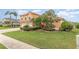 Landscaped front yard with lush green grass, manicured shrubs, and tropical plants at 2326 Wintermere Pointe Dr, Winter Garden, FL 34787