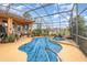 A screened in pool is covered with a blue tarp and surrounded by greenery, with a lake view beyond the enclosure at 2326 Wintermere Pointe Dr, Winter Garden, FL 34787