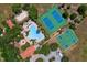 Aerial view of the community pool, tennis courts, beach volleyball, and basketball court amidst lush greenery and manicured lawns at 2333 Pesaro Cir, Ocoee, FL 34761