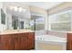 Bathroom featuring a soaking tub, double vanity with wood cabinets, and a large bright window at 2333 Pesaro Cir, Ocoee, FL 34761