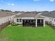 A view of the lush green backyard with a screened-in porch, hot tub, and neatly manicured lawn at 2949 Marlberry Ln, Clermont, FL 34714