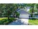 View of the home's exterior showing the garage, well-maintained lawn, and mature trees providing shade at 418 S Summerlin Ave, Sanford, FL 32771