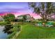 Lovely backyard view with pond, lush green lawn, mature trees, and fire pit area for outdoor enjoyment at 53 Fore Dr, New Smyrna Beach, FL 32168