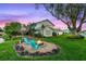 Beautiful backyard with a fire pit, mature trees, and manicured lawn overlooking the tranquil pond at 53 Fore Dr, New Smyrna Beach, FL 32168