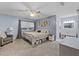 Light-filled bedroom with a bed, ceiling fan, large window, and an attached bathroom at 53 Fore Dr, New Smyrna Beach, FL 32168