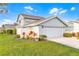 Charming home featuring a two-car garage with a manicured lawn, flowers, and white fence at 53 Fore Dr, New Smyrna Beach, FL 32168