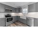 Modern kitchen with stainless steel appliances, white subway tile backsplash, granite countertops, and gray cabinets at 53 Fore Dr, New Smyrna Beach, FL 32168
