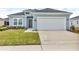 Charming single-story home featuring a light blue exterior, well-maintained lawn, and a two-car garage at 7412 Sw 76Th Ter, Ocala, FL 34481
