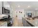 Modern kitchen showcasing stainless steel appliances, granite countertops, and seamless flow to the living area at 7630 Oakmoss Loop, Davenport, FL 33837