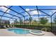 Enclosed pool and hot tub with lounge chairs, greenery and views at 7630 Oakmoss Loop, Davenport, FL 33837