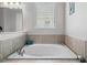 Soaking tub offers a relaxing retreat with tile surround, a window for natural light, and sleek fixtures for a spa-like experience at 7702 Fairfax Dr, Kissimmee, FL 34747