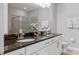 Bathroom with double sinks, granite countertop, white cabinetry, and shower at 7702 Fairfax Dr, Kissimmee, FL 34747