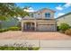 Charming two-story home with a brick driveway, manicured landscaping, and a two-car garage at 7702 Fairfax Dr, Kissimmee, FL 34747